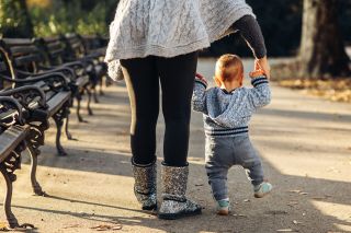 Mom teaching her son's first baby steps in the park